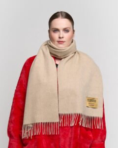 Close-up of hands presenting a neatly wrapped Scott Cashmere scarf in a heritage-inspired gift box.