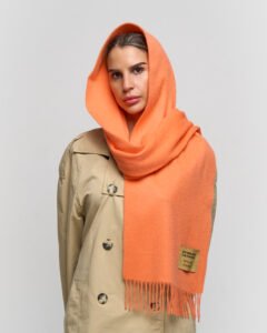 A premium navy and green tartan scarf draped over a luxury travel trunk, symbolising global reach and heritage.
